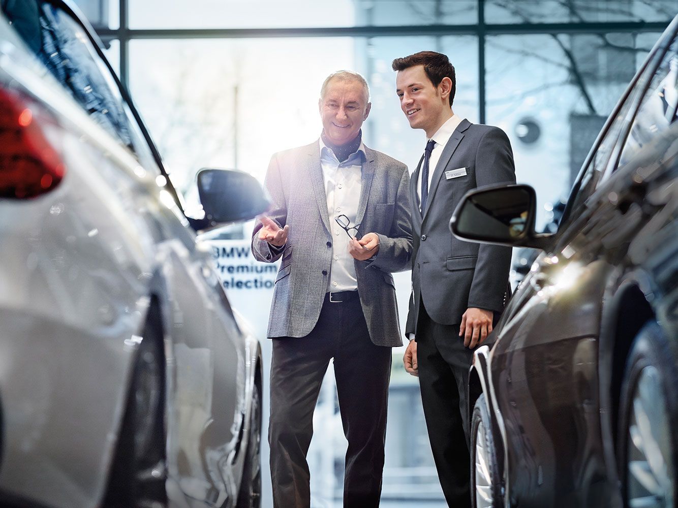 Verkäufer, der einem Kunden bei der Auswahl eines BMW Premium Selection Fahrzeugs hilft